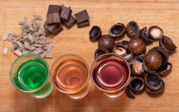 Tres tragos con diferentes bebidas alcohólicas se colocan sobre una base de madera —  Fotos de Stock