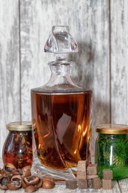 A curved crystal decanter with homemade moonshine stands on a wo
