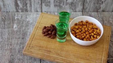 Yeşil apsent ve farklı aperatifler ile iki shot ahşap bir stantta döner.