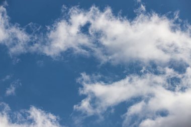 Aydınlık, beyaz bulutlar güneşli bir günde mavi bir gökyüzünde