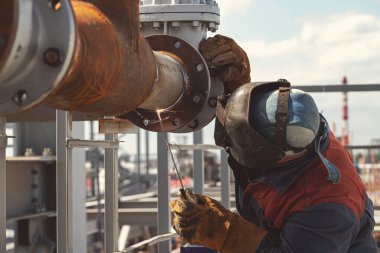 Kaynakçılık, yeni petrol arıtma tesisatı boru hattının elle kaynaklama kullanılarak kurulumunda çalışır.