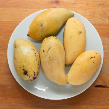 Beyaz ahşap arka planda mango sarısı.