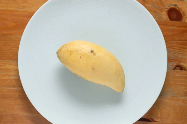 Mango amarillo sobre fondo de madera blanca plato . — Foto de Stock