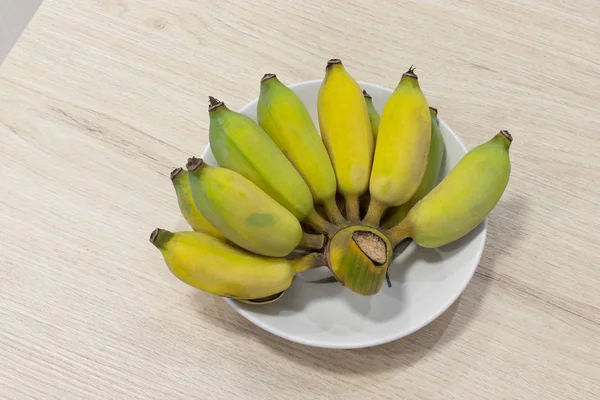 Banana em prato branco em madeira de mesa . — Fotografia de Stock