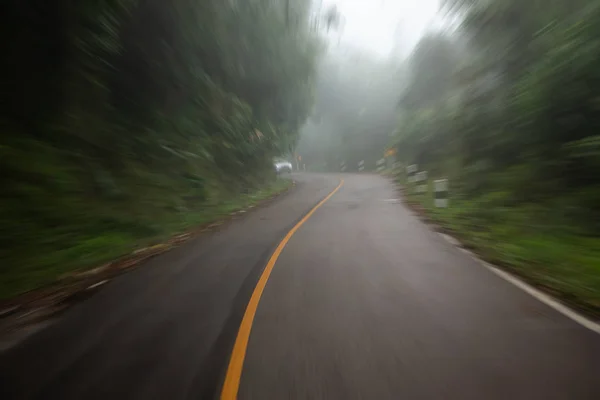 Strada appannata sulla montagna con un'auto sullo sfondo . — Foto Stock