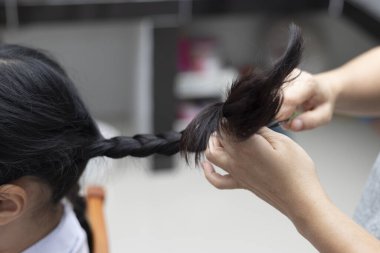 Kızının uzun saçlarını örten bir kadın..