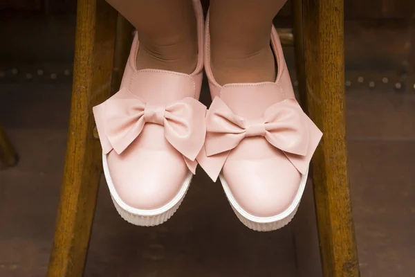 Pink shoes with bows on the legs of a girl