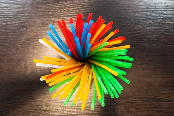 On the table in a white paper cup are colored cocktail tubes