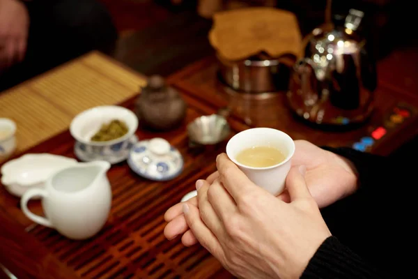 A white cup with green tea in the hands of a girl.