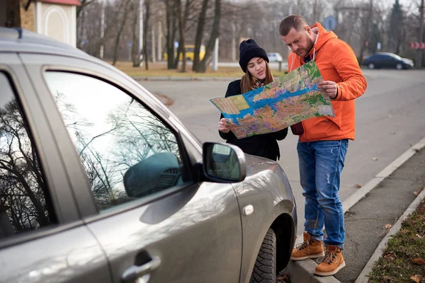 Map in the hands of young people on the road with a car.