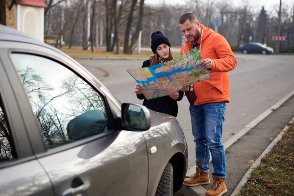 Map in the hands of young people on the road with a car.