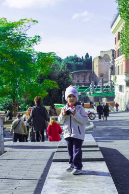 Roma. 10.11.2019, güneşli bir günde sokakta kamerası olan küçük bir çocuk.