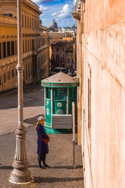Roma, 10.11.2019, della Dataria üzerinden reklam okuyan bir kız. Güneşli bir günde Aziz Peter Katedrali manzarası.