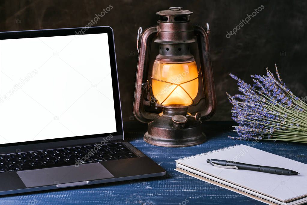 A laptop with a blank screen is on a blue table next to a bouque