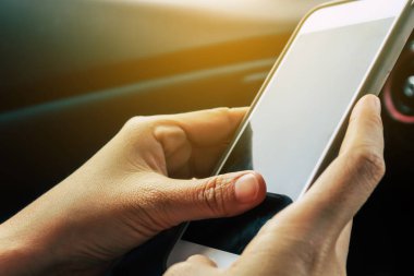 Bir arabanın içinde akıllı telefon kullanan insanların görüntüsü.