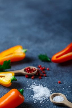 Sarı ve turuncu peppe ile masada kaşık içinde farklı baharatlar