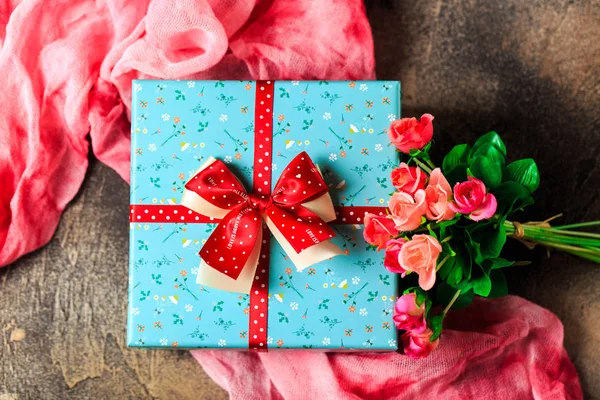 Scatola regalo blu con fiori e nastro rosso con fiori di rosa su b — Foto Stock