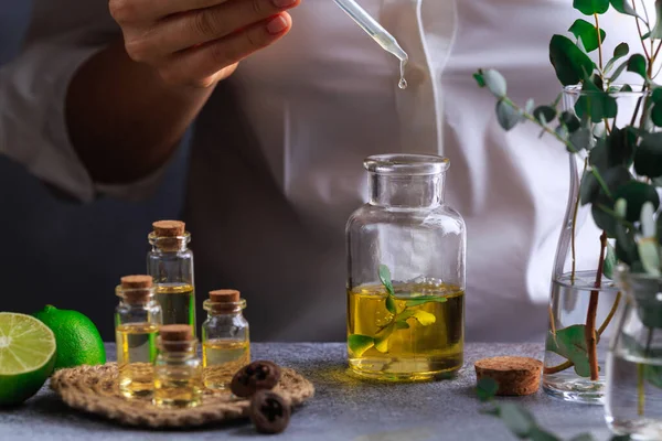 Mujer mano verter aceite esencial de eucalipto en botella sobre mesa gris — Foto de Stock