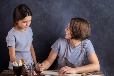 Anne ve kızı birlikte Noel ağacı oyuncağı yapıyorlar. Gri arka plan. Yeni yıl faresinin sembolü..