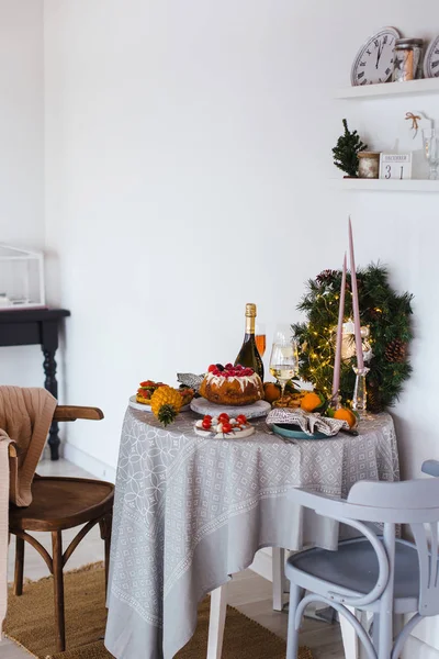 Konzept von Weihnachten. Tisch mit Lebensmitteln und Silvesterutensilien steht in einem Raum, der für Neujahr dekoriert ist — Stockfoto