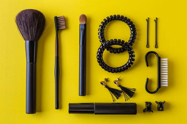 Escova de maquiagem preta e cosméticos em amarelo flat lay — Fotografia de Stock