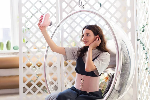 La chica se sienta en una silla transparente y toma una foto selfie en la cámara instantánea — Foto de Stock
