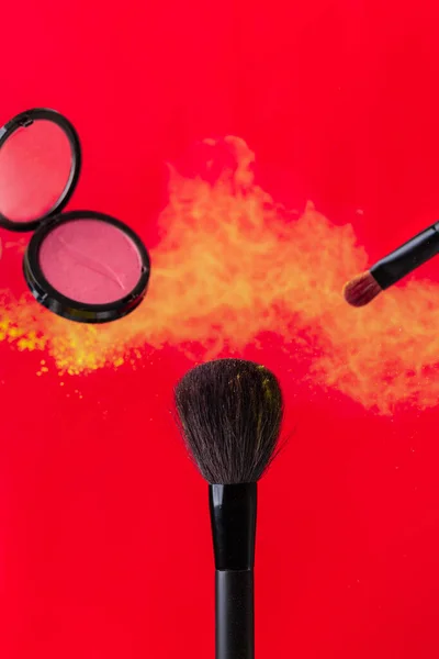 cosmetic brush and sprayed cloud of cosmetics on a red concept