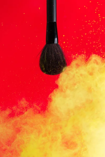 cosmetic brush and sprayed cloud of cosmetics on a red concept