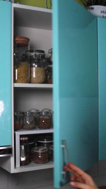 Kadın eli mutfak rafını açar ve HD dikey video ile teneke kutuyu alır.