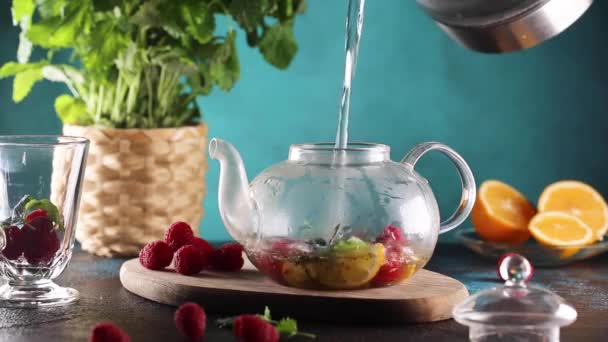 Процесс заливки горячей воды в стеклянный чайник с травой и малиной видео hd — стоковое видео