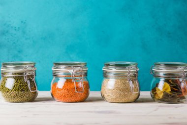 İçinde kinoa, mercimek, püre, makarna bulunan cam kutular ve şişeler. Basit, şık bir ev. Plastik yok.