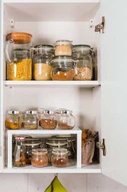 Mutfaktaki raflarda cam kavanozlarda çeşitli tahıl ve tohumlar var.