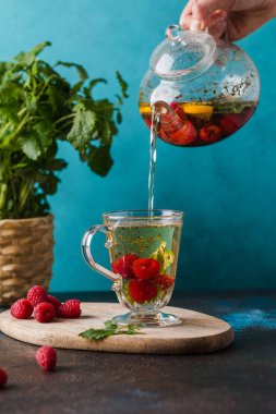 Ahududu ve nane çayı, tahtadan yapılmış mavi duvara dökülüyor.