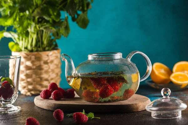 Theepot met frambozen thee munt bladeren en citroen op blauw — Stockfoto