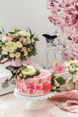 Çiçeklerle süslenmiş pembe pasta ve gerçek kelebekler romantik bir atmosfer yarattı.