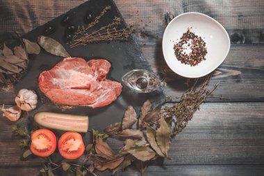 Koyu bir tezgahın üzerinde, büyük bir parça çiğ et, süslenmiş. 