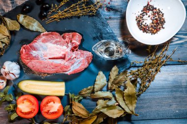 Koyu bir tezgahın üzerinde, büyük bir parça çiğ et, süslenmiş. 