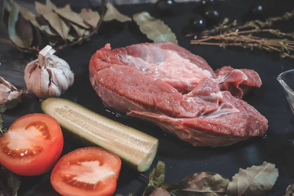A piece of raw beef is laid out on a dark wooden tabletop on a g — Stock Photo, Image