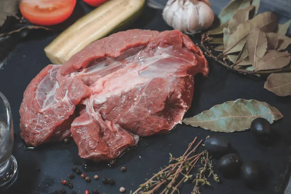 On a dark countertop, a large piece of raw beef, garnished with — Stock Photo, Image