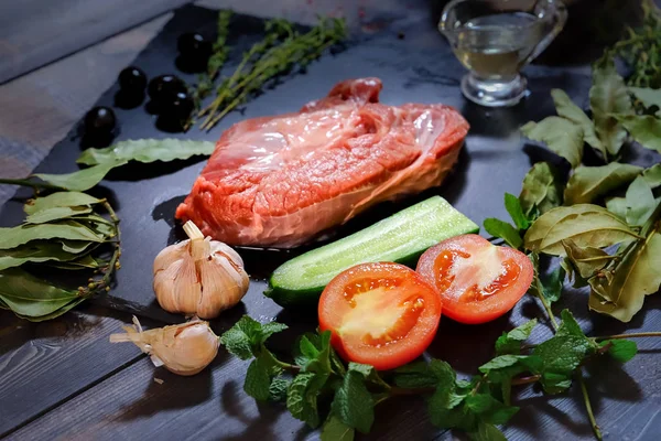 Un trozo de carne cruda se coloca en una mesa de madera oscura en un g Fotos de stock libres de derechos