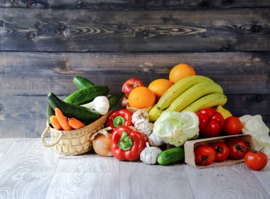 Grafit ahşap zemin üzerinde sebzeler ve meyveler: bir kutunun içinde domates, salatalık, sarımsak, büyük kırmızı biber, Iceberg marulu, şalgam soğanı, muz, bir elma, yanında taze havuç, salatalık ve taze sarımsak bulunur. Durgun hayat, 