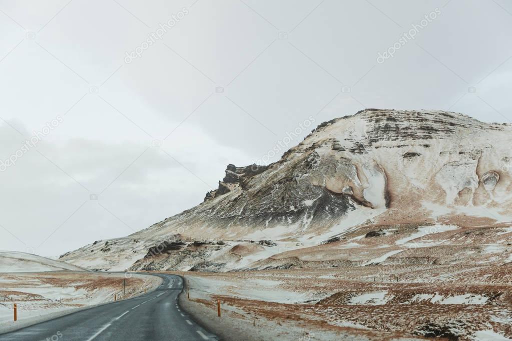 empty asphalt road and scenic snow-covered mountains in iceland  