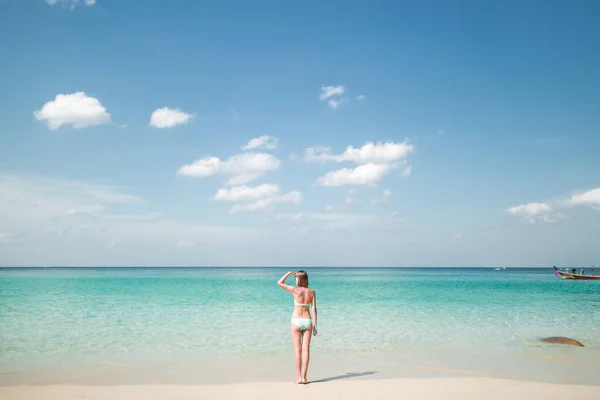 PHUKET, TAILANDIA - 20 DE DICIEMBRE DE 2015: Vista trasera de la mujer en bikini mirando hacia otro lado mientras está de pie en la costa - foto de stock