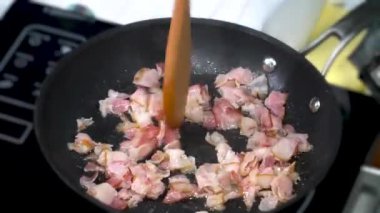 Pieces of bacon are fried in a pan
