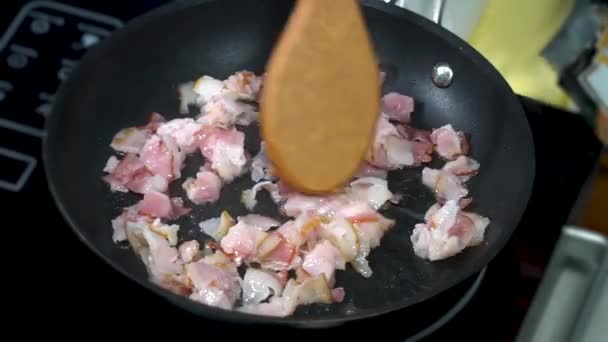 Куски бекона поджариваются на сковороде. — стоковое видео