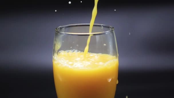 A stream of orange juice fills a glass — Stock Video