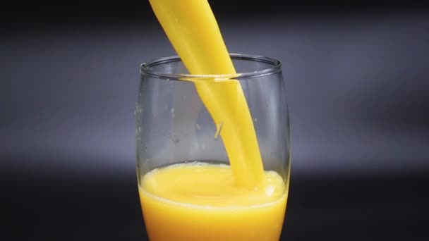 Поток апельсинового сока наполняет стакан — стоковое видео