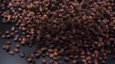 Kahve çekirdekleri siyah bir yüzeye dökülür..