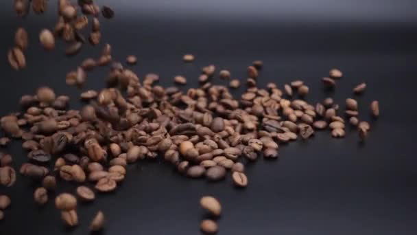 I chicchi di caffè sono versati su una superficie nera . — Video Stock