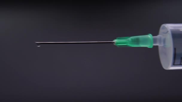 Une aiguille libère une goutte de liquide transparent 